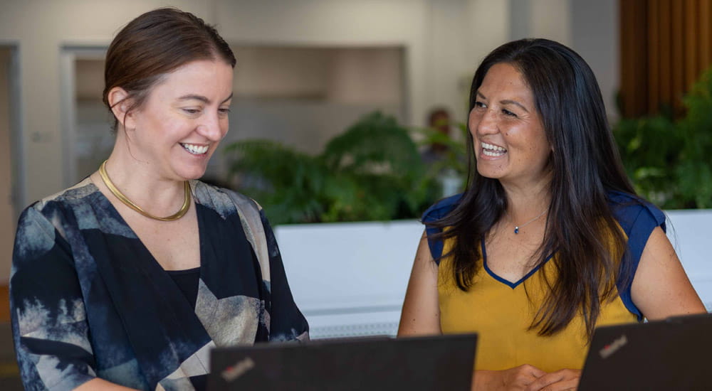two women talking at desk