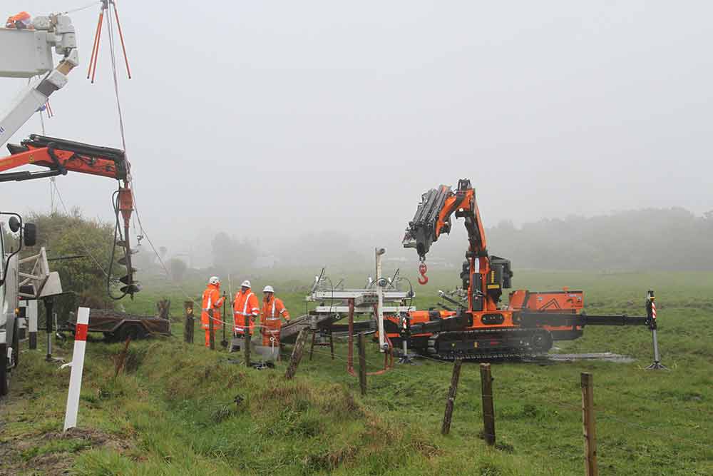 Crew and machinery in a field on a misty day.