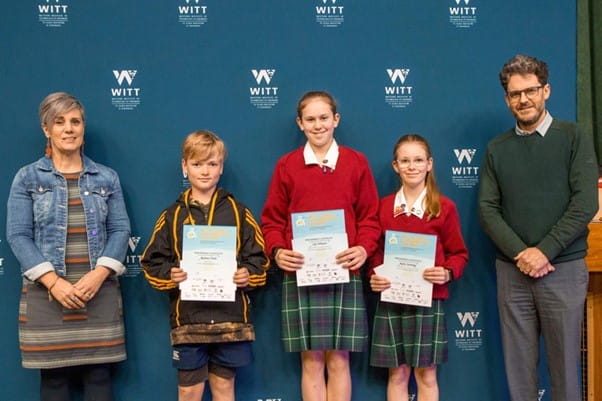 A woman standing next to three children who are holding certificates