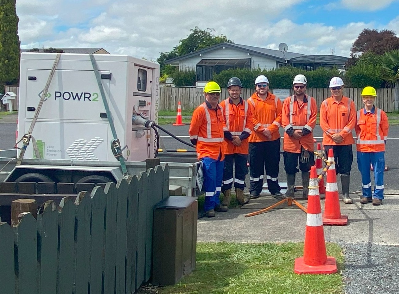 Six people in high-vis standing next to a large white container on a trailer 