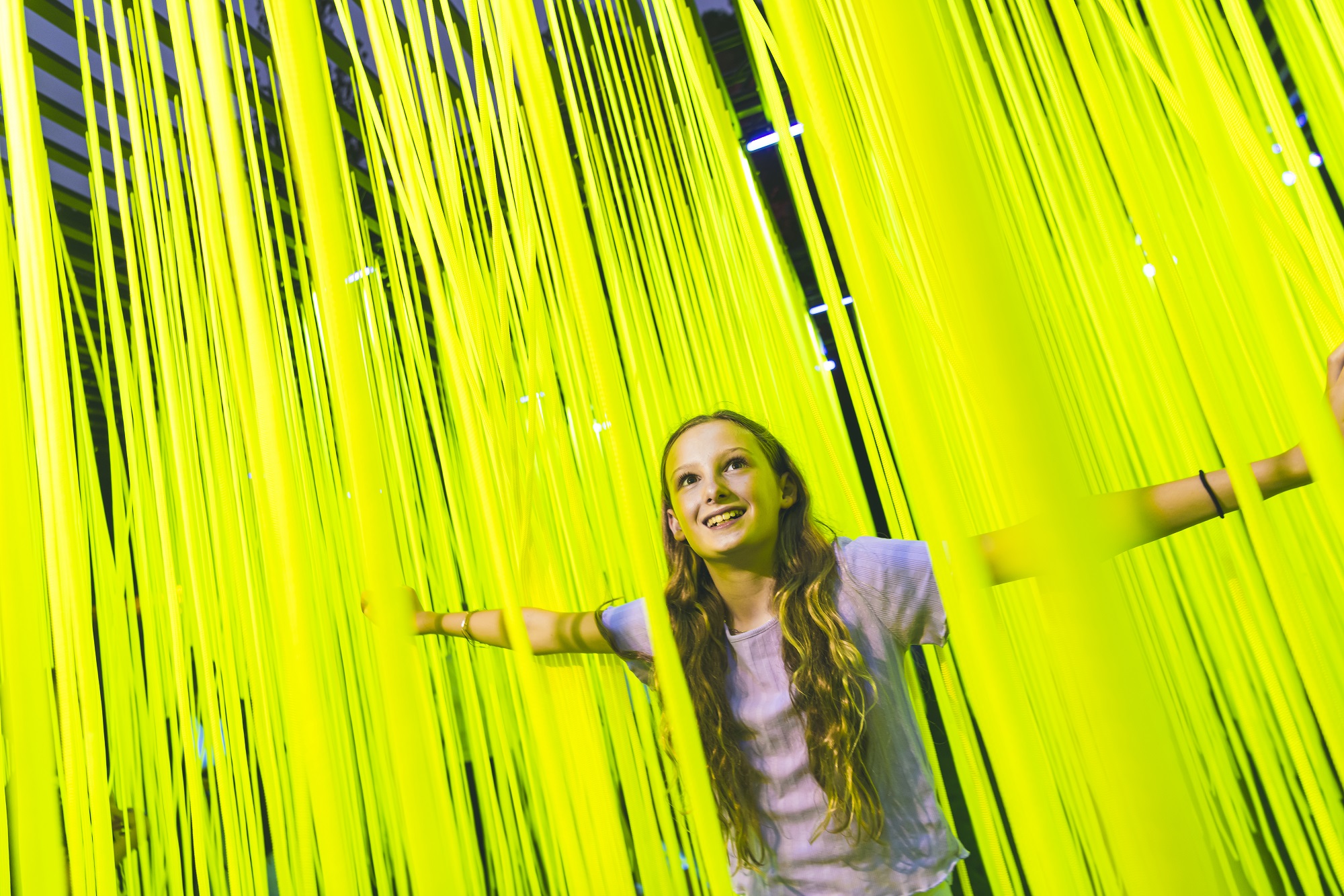 Young girl with long blond hair admidst fluorescent spagetti-type lights