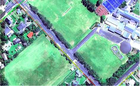 A satellite image showing bird's eye view of green fields, trees and buildings