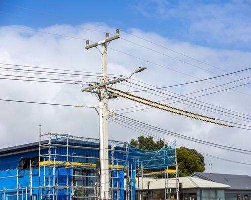 A building site with scaffolding and a power pole and power lines in front