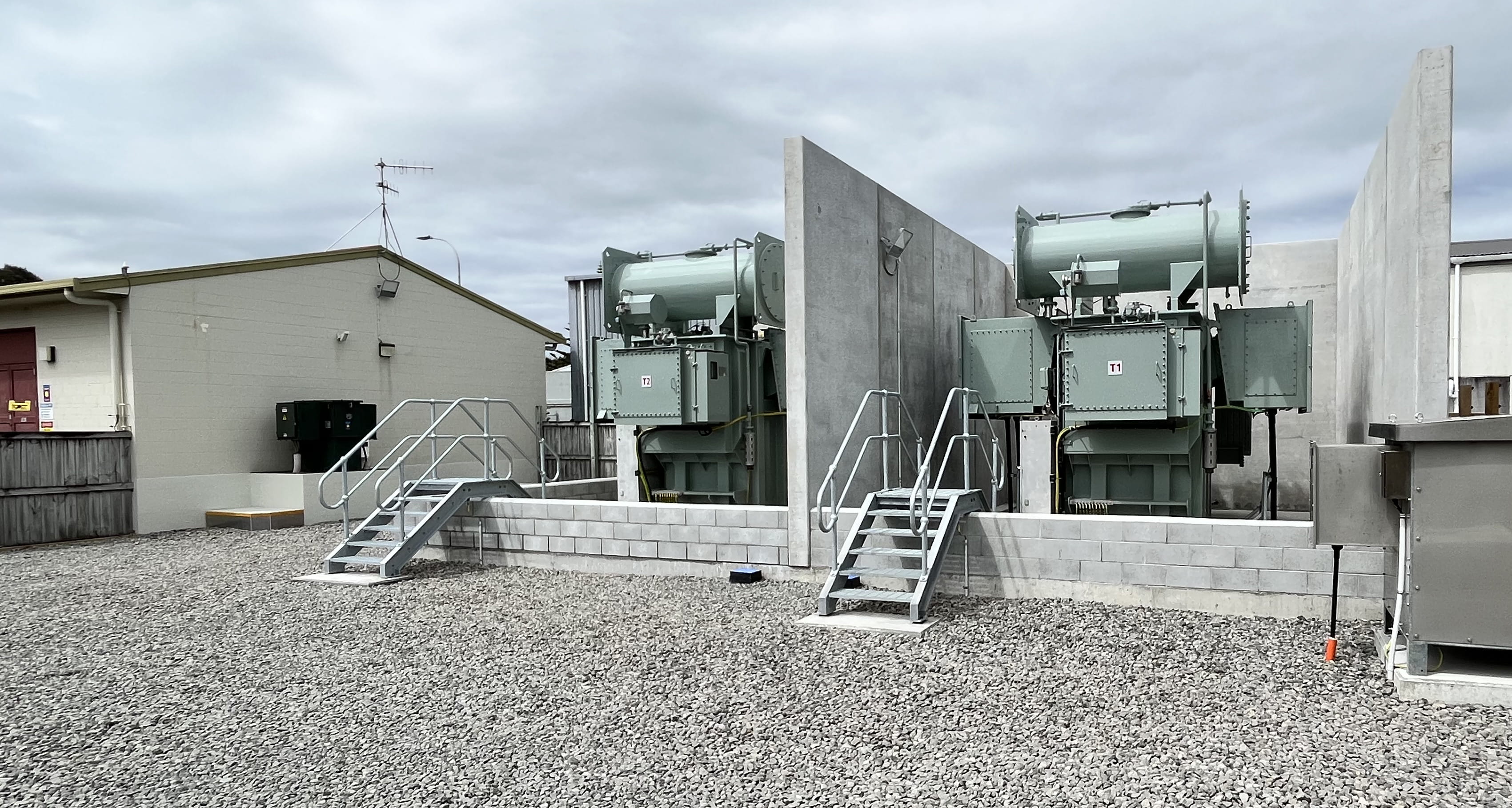 Two large outdoor transformers in an electricity substation yard.