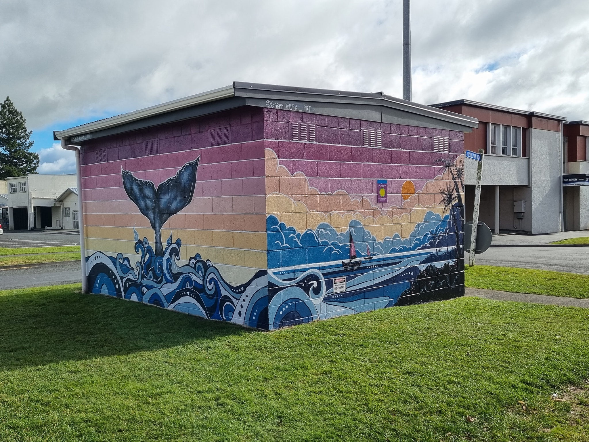 A small concrete block building featuring a mural with a tropical ocean scene.