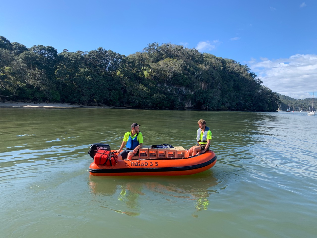 Two men in an inflatable dingy on the water in a bay