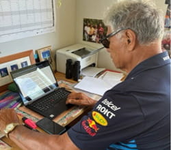 man sitting at desk looking at laptop
