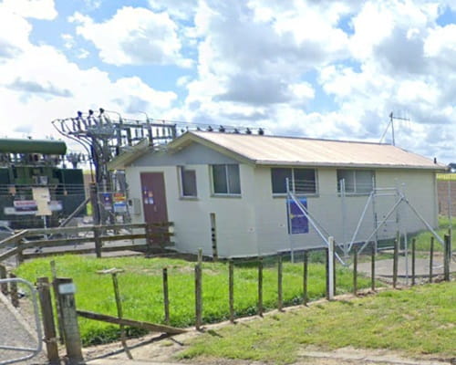 A small building in a rural setting with power lines in the background. 