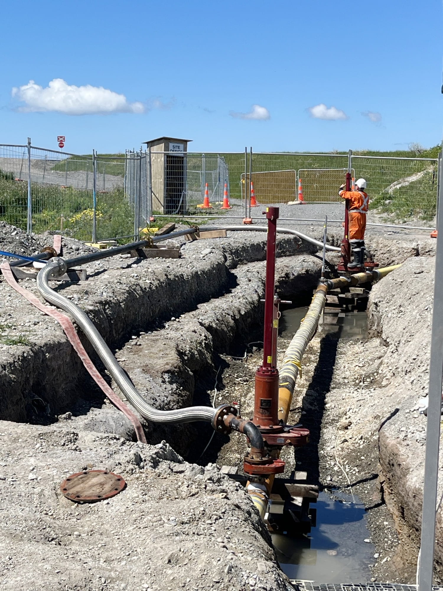 A man in PPE working on a new gas pipe in the ground.