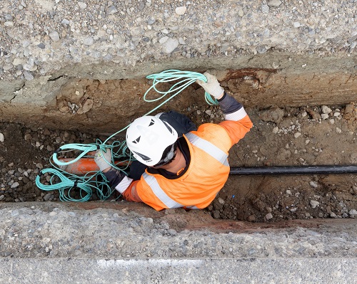 Aerial view of a contractor in a trench laying an electricity cable.