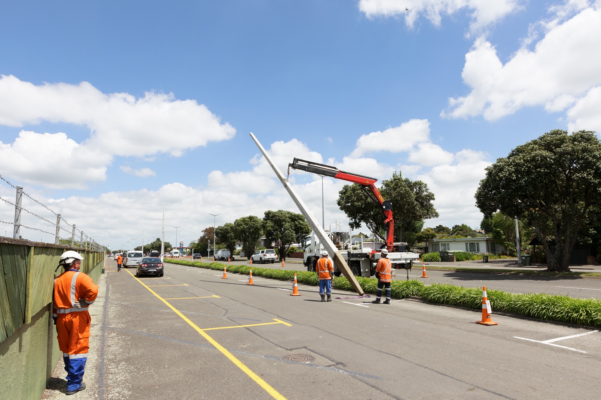 A hyab truck and workman bringing down a concrete power pole to the road.