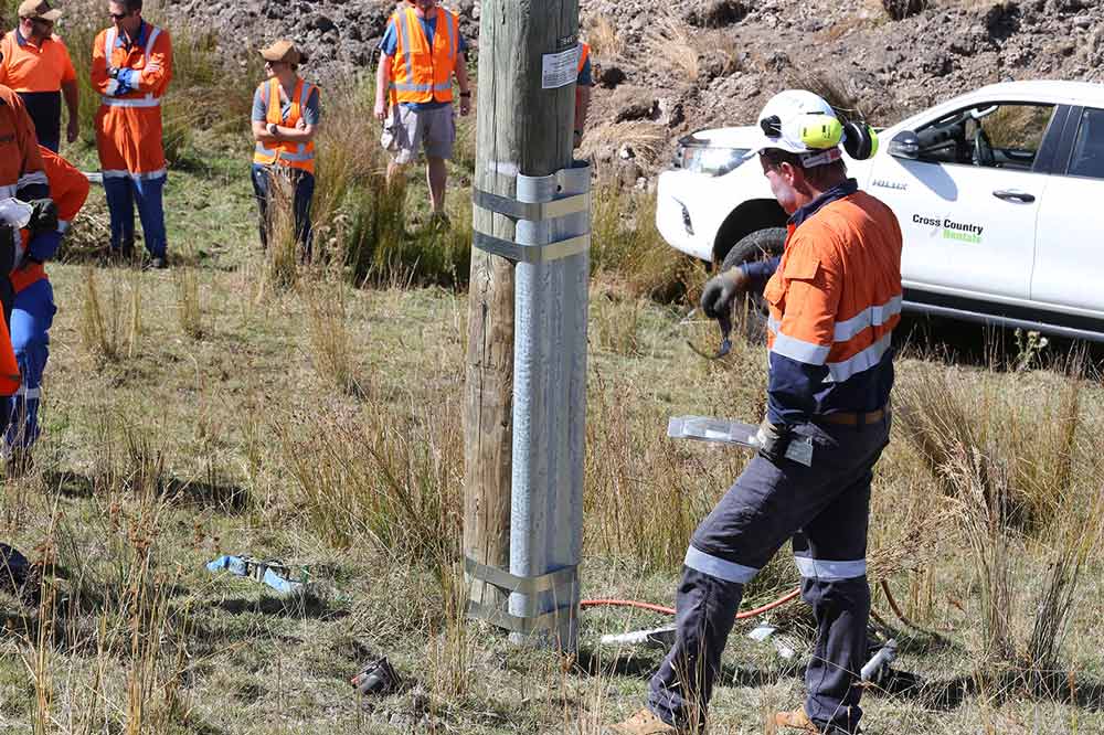 Field crew reinforcing a wooden pole