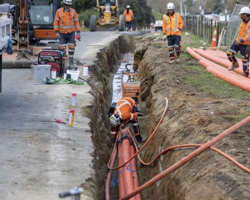 Crews installing underground electricity cable in a trench