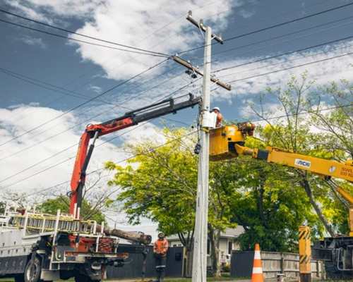 Field crew upgrades overhead electricity line from a cherry picker