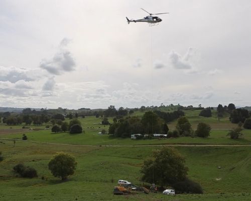 Helicopter delivering a hopper of concrete to site in South Waikato countryside.
