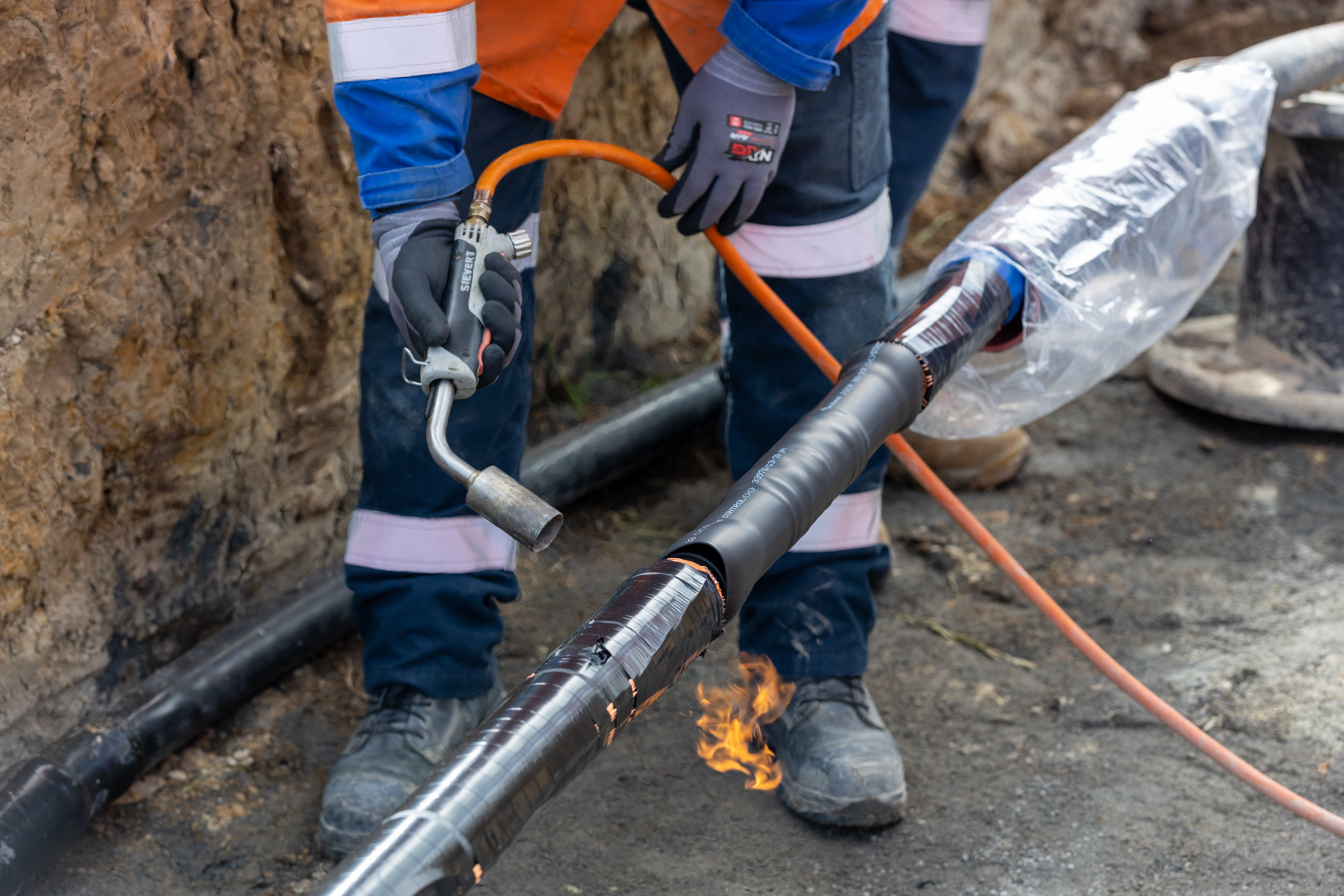 Field crew using a blowtorch to do cable jointing in a trench