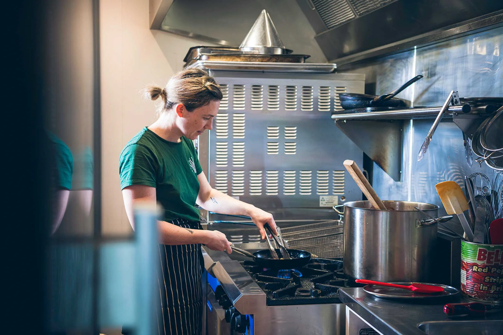 woman cooking on gas stove in commercial kitchen