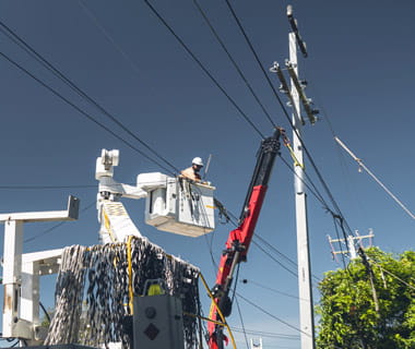 person in bucket trucking fixing power pole