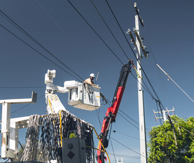 person in bucket trucking fixing power pole